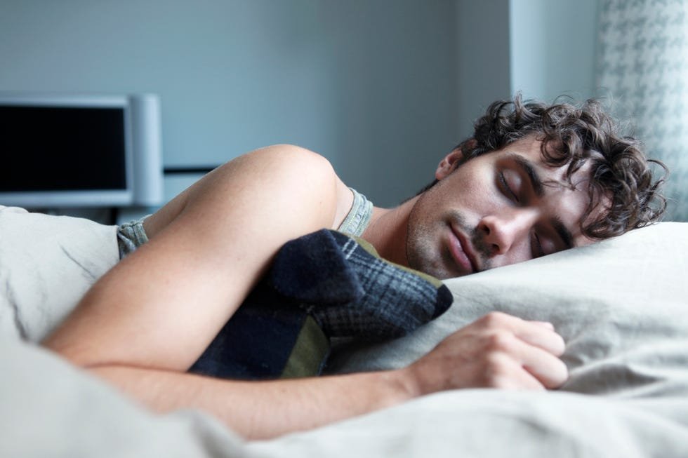 man sleeping in bed with stuffed animal